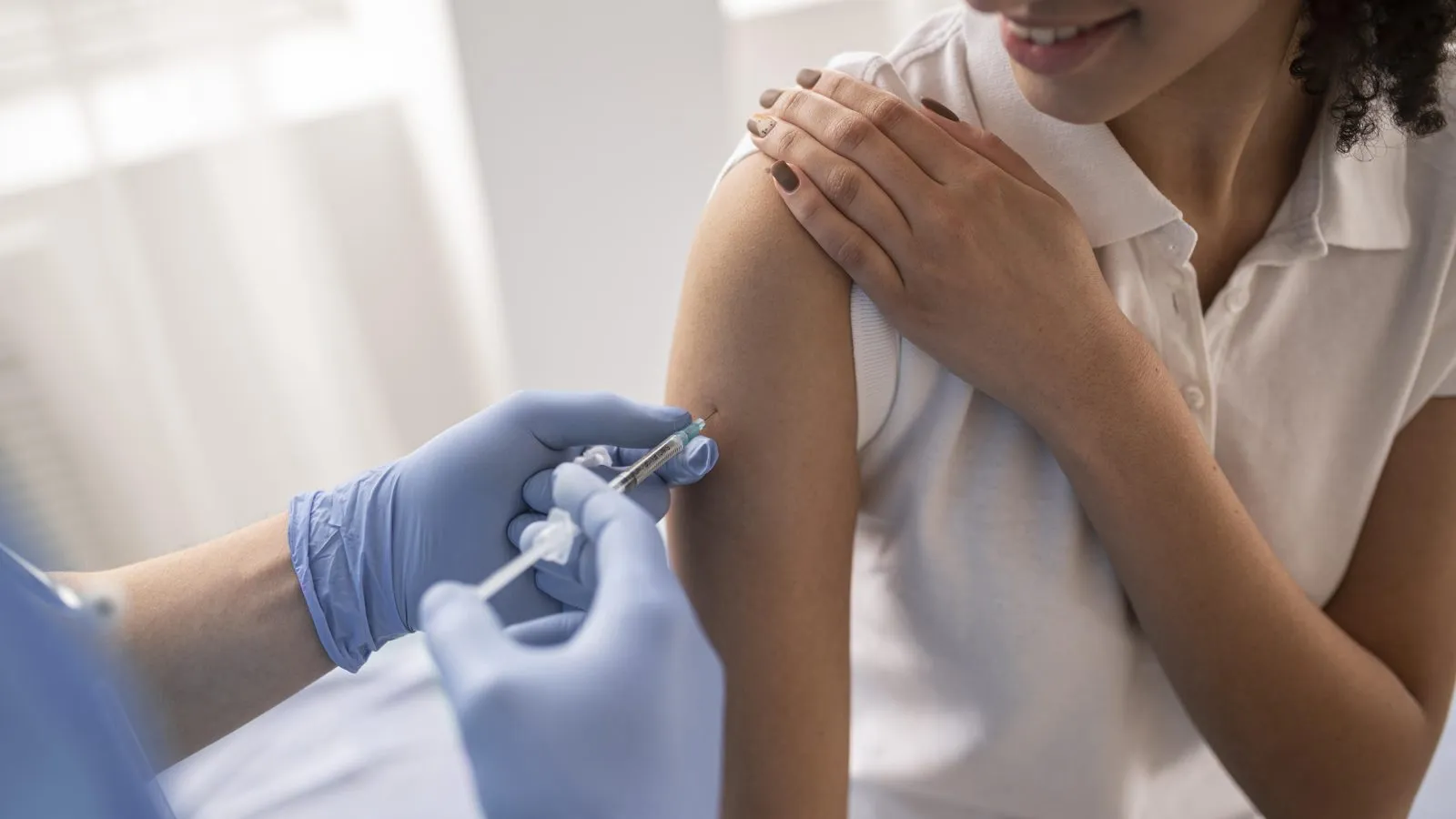 Doctora aplicando una vacuna en el brazo de una paciente sonriente